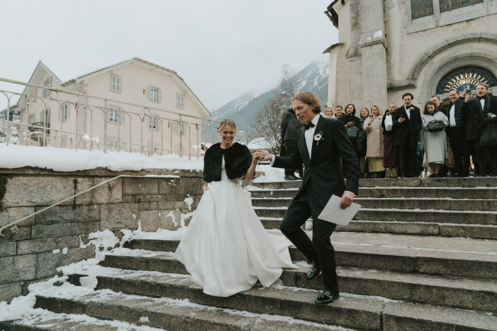 Married couple walking down the stairs outside saint michel church chamonix for their mountain wedding