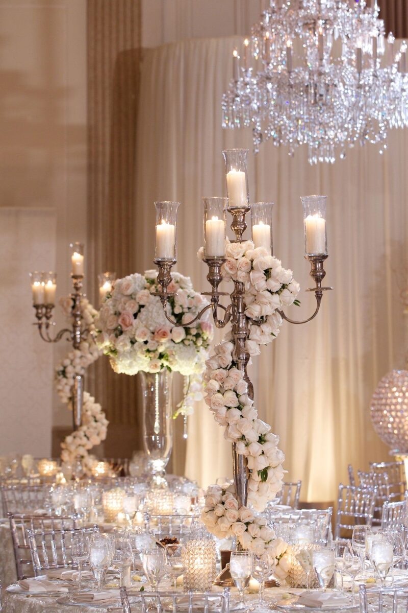 Tall candles and chandelier used to style a wedding celebration ready for luxury catering